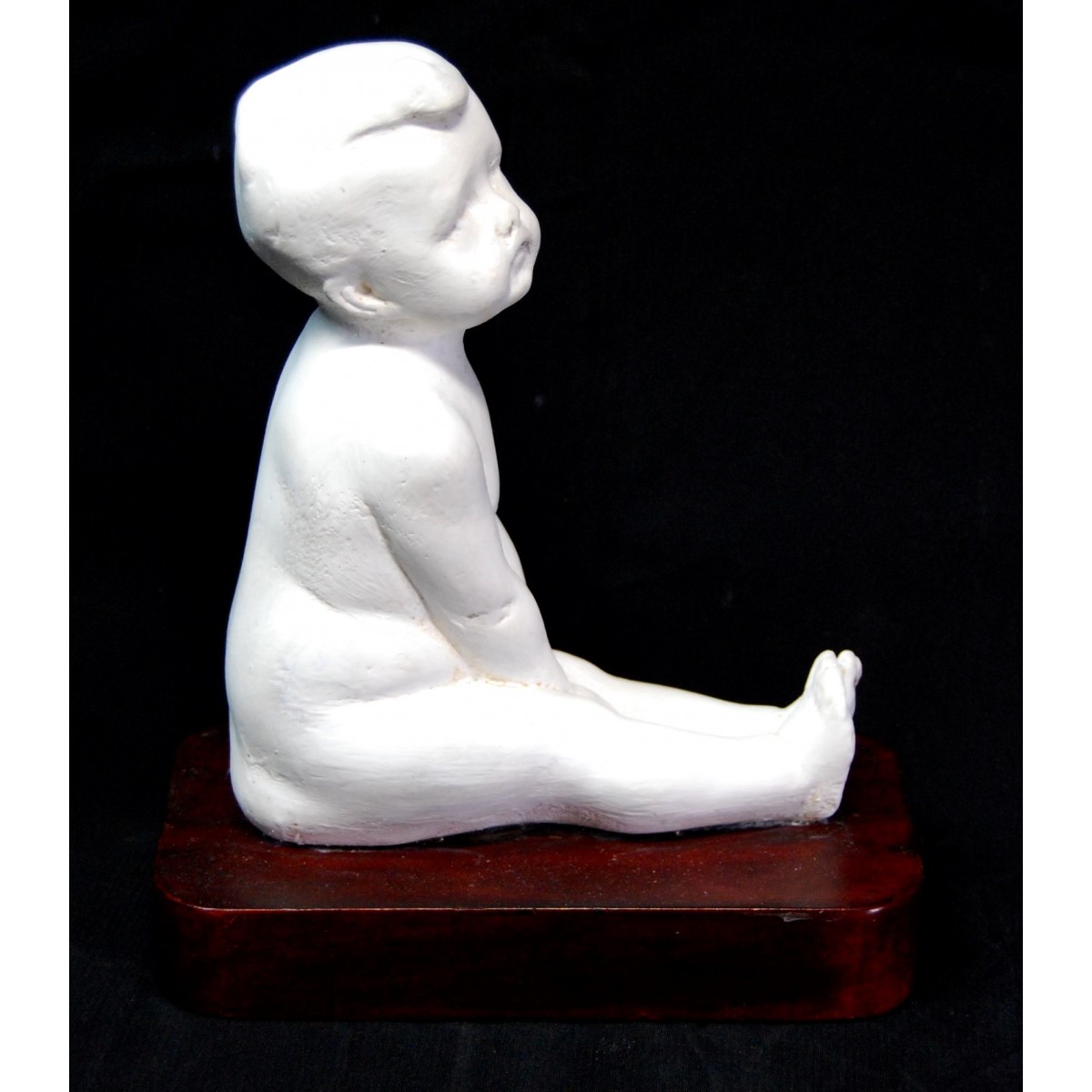 Figura de niño desnudo sentado.