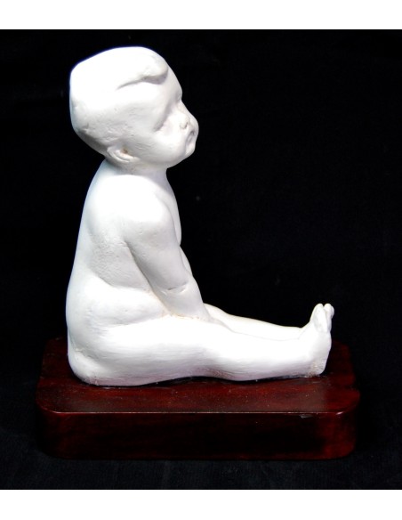 Figura de niño desnudo sentado.