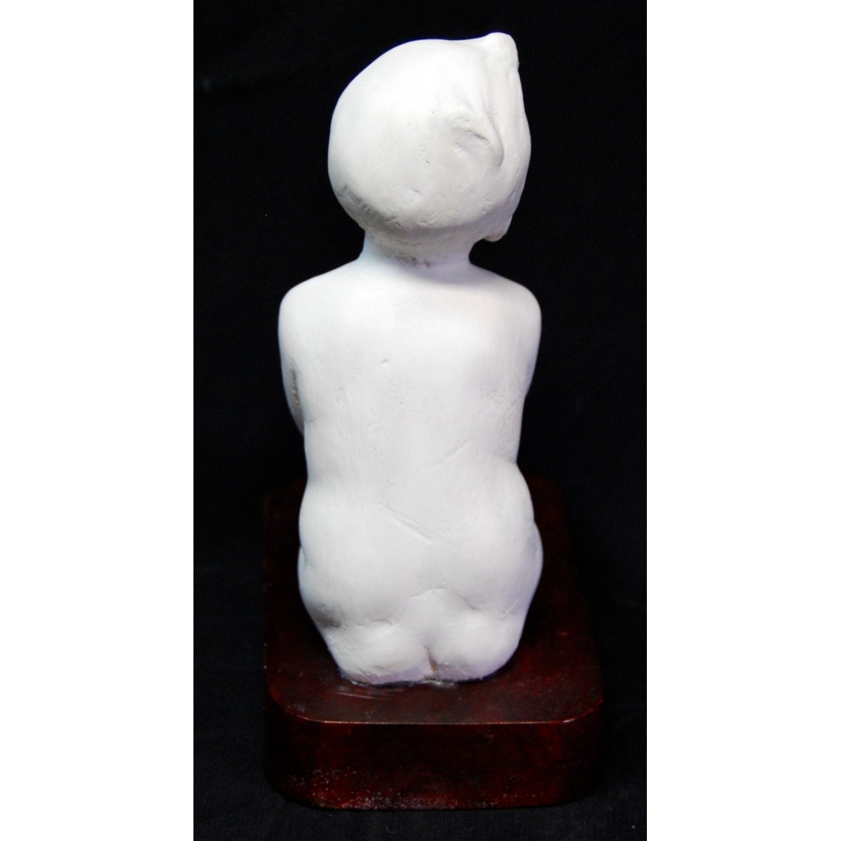 Figura de niño desnudo sentado.