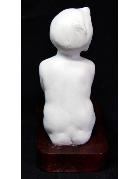Figura de niño desnudo sentado.