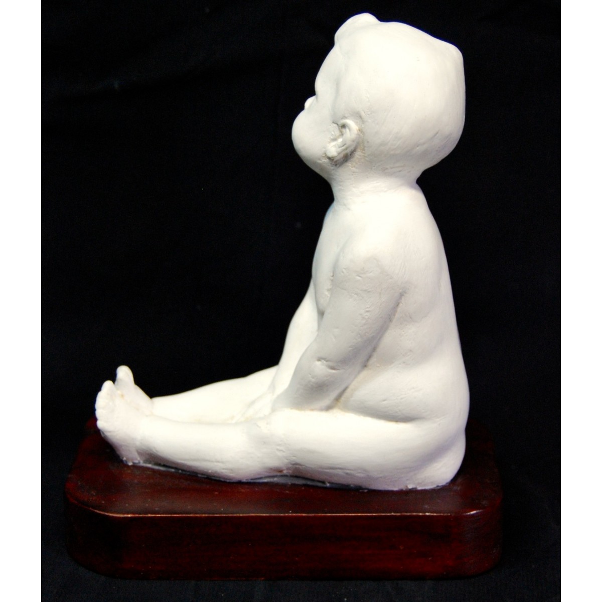 Figura de niño desnudo sentado.