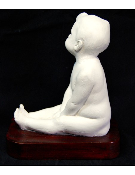 Figura de niño desnudo sentado.