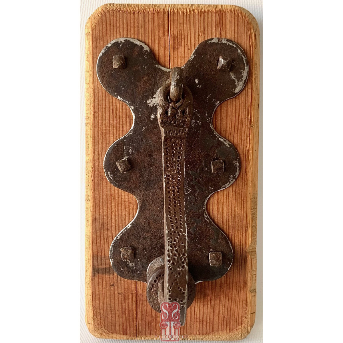 Aldaba llamador de hierro forjado y cincelado, de forma curvada en la parte inferior, siglo XVIII.