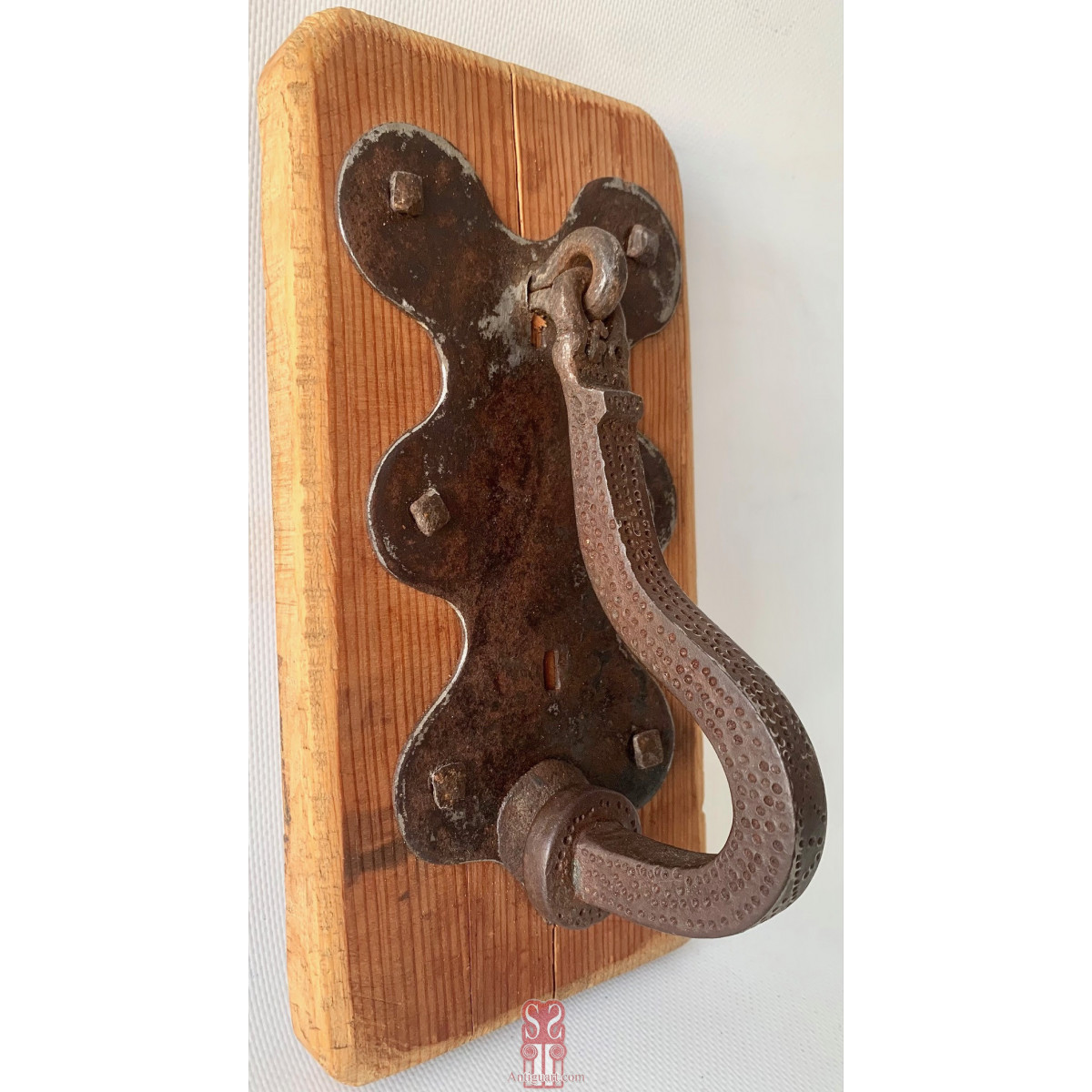 Aldaba llamador de hierro forjado y cincelado, de forma curvada en la parte inferior, siglo XVIII.